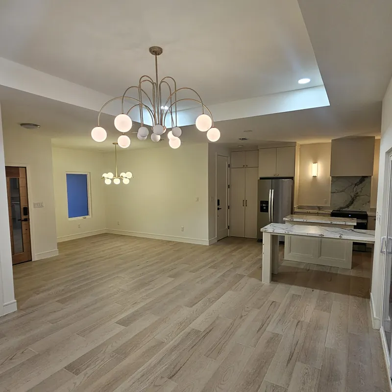 Photograph of the finished dining and living space with a globe chandelier.