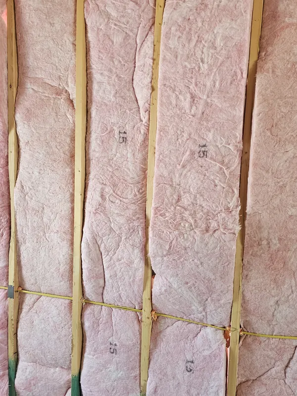 Close-up photograph of insulation batts between the studs of one wall.